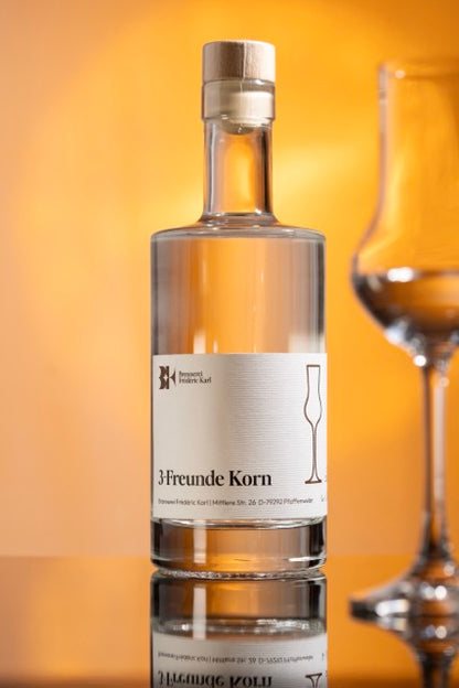 Der Drei-Freunde-Korn der Brennerei Karl abgebildet mit einem Glas und vor einem Orangenem Hintergrund.